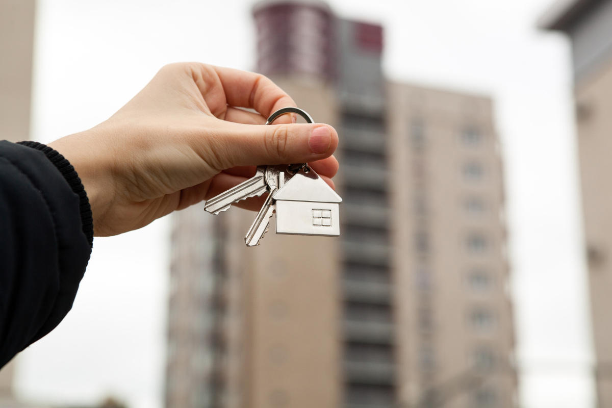 Hand holding up a set of keys with a house shaped keyring